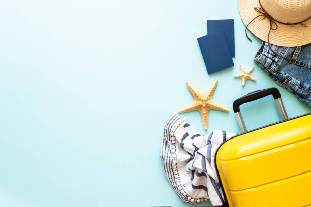 istock Suitcase, passports, hat and summer cloth on blue background. 1927790663