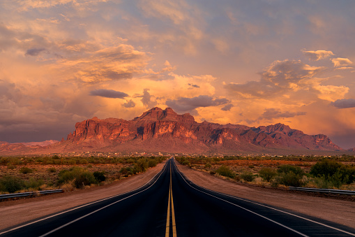 Long, straight road to the Superstition Mountains in Arizona at sunset.