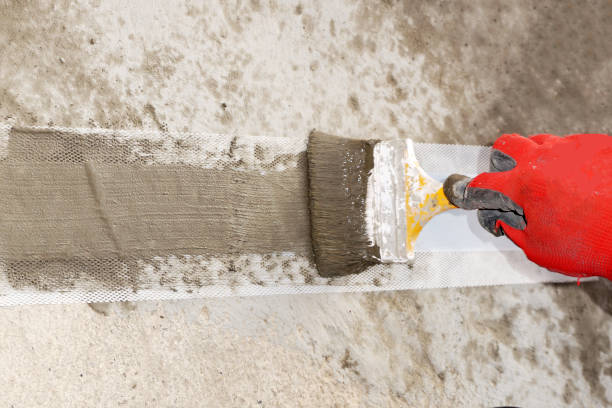 istock a worker's hand applies a waterproofing solution with a brush to a special waterproofing tape 1927813743