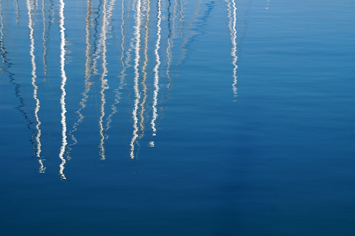 yachts match reflected in blue sea water.