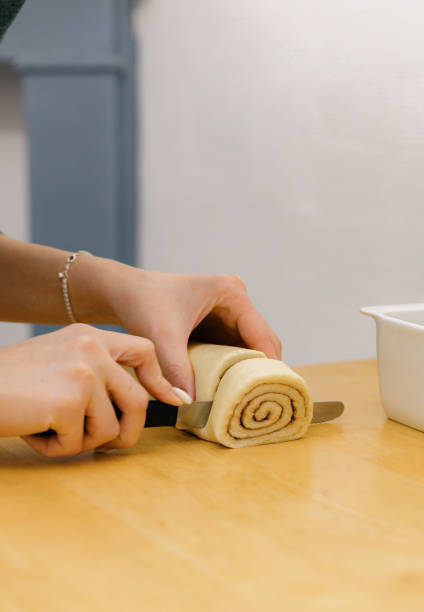 istock One Caucasian young girl cuts cinnamon dough into pieces on the table. 1927830133