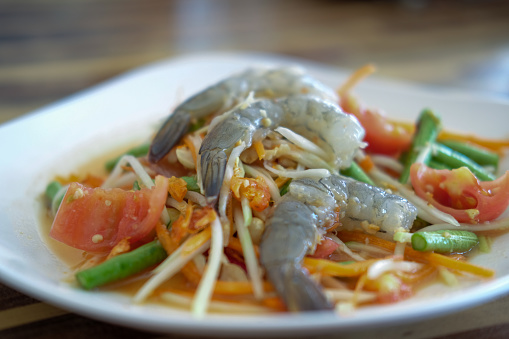 Som Tum, Thai papaya salad with raw shrimp served on plate.