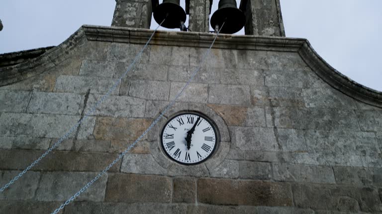 Heavy wooden doors with stone coat of arms and clock with bell tower on outside of church