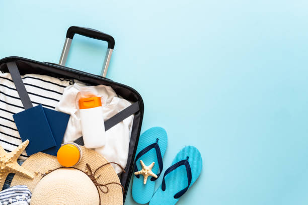 istock Suitcase, hat, passports and flip flops on blue background. 1927846497