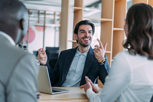 Shot of group of business persons in business meeting. Three entrepreneurs on meeting in board room. Corporate business team on meeting in modern office. Male manager discussing new project with his colleagues. Company owner on a meeting with two of his employees in his office.