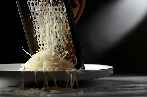 Grated cheese and grater. Concept: Italian cuisine, cheese, restaurant, and food. Copy space.