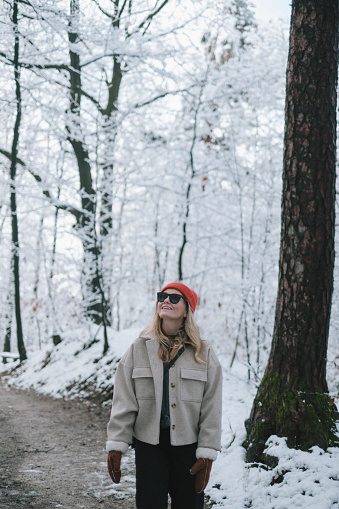 Young woman enjoys snow in forest wearing red hat