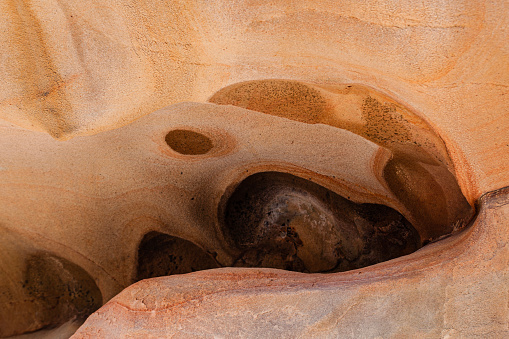 Photograph of a rock with orange and ochre colors with abstract shapes in the cliffs of Jaizkibel, copy space