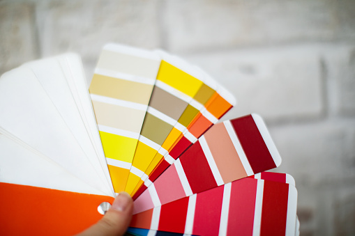 Top view of interior designer holding fan of colourful samples in hand. Woman searching proper colour for promotion. Design and art concept