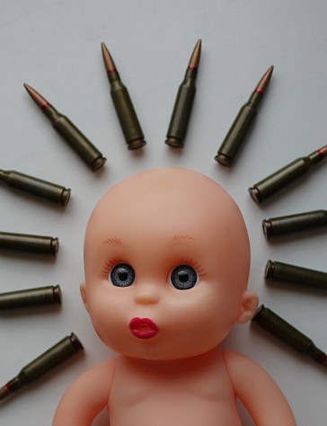 Live ammunition is placed around the doll's head with sad eyes