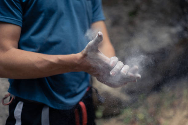 Unrecognizable climber put climbing chalk on hands in order to improve friction and grip