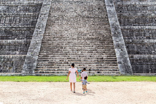 A snapshot of people who observe an ancient architectural structure with several stairs, in the shape of a pyramid.