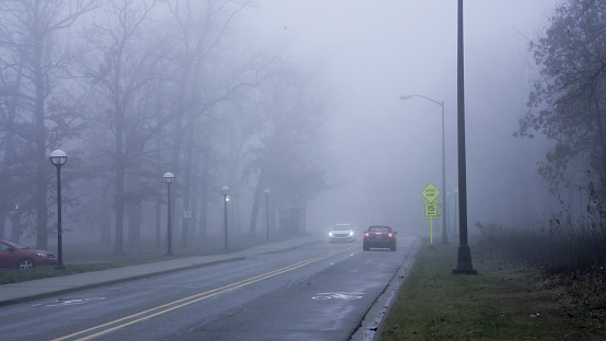 A misty urban street enveloped in fog on a gloomy overcast day