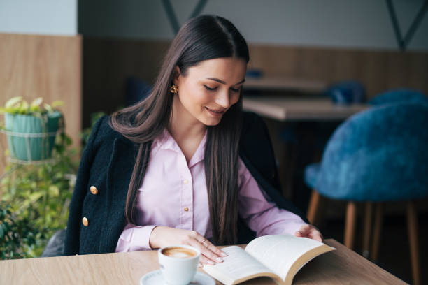 istock Attractive young woman reading a book while drinking coffee 1928183521