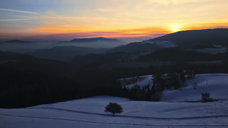 AERIAL Drone Shot of Beautiful Snow Covered Mountain Landscape under Orange Sky at Sunset in Rogla, Slovenia