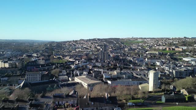 An aerial liftoff with drone above Cork City in winter sunny day with rooftops and church towers