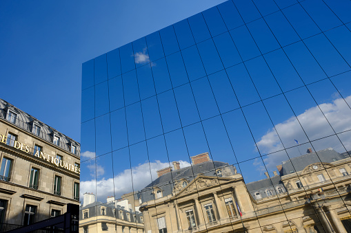 Paris, France — September 15, 2023: Reflection of the Louvre in modern glass building. Image made in Palais Royale Square.