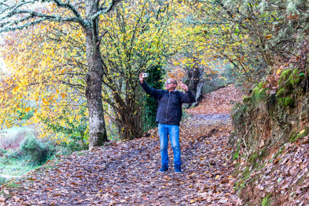 hombre de mediana edad se está tomando una selfie con su teléfono inteligente - con trail - fotografias e filmes do acervo