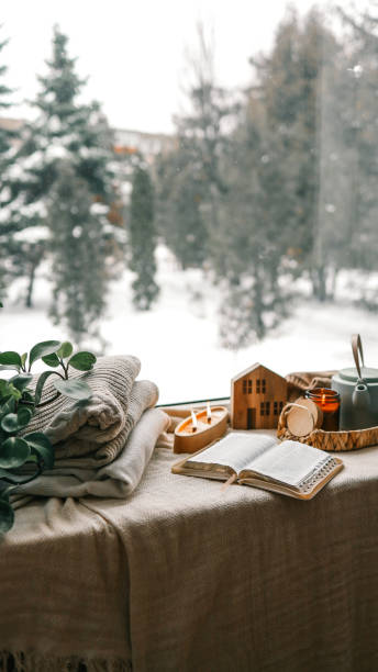 istock Cozy winter photo, stack of sweaters, open Bible, tea and candle 1928359137