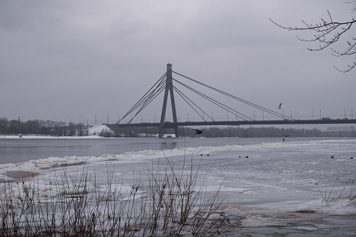 Kyiv, Ukraine - January 11, 2024. Outside, the temperature is sub-zero and frosty. A beautiful bridge can be seen behind. Light snow falls and sprinkles the city. A little fog begins and the sky is very gray.