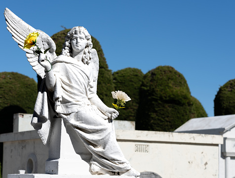 angel statue with flowers in hands, on a clear sky