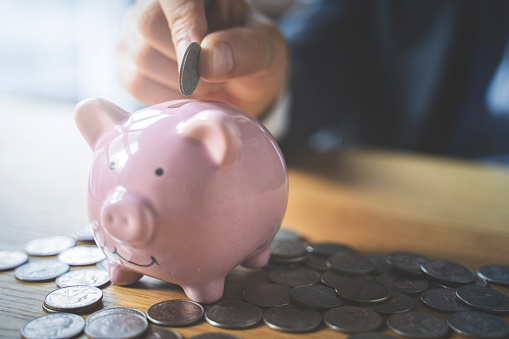 Man putting a coin into a pink piggy bank