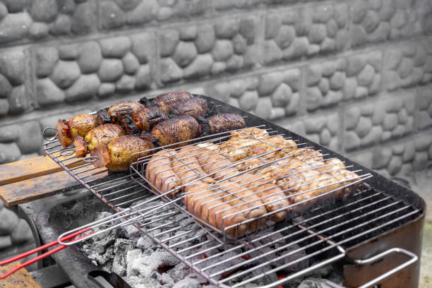 Grilled sausages and bacon with potatoes on bbq.