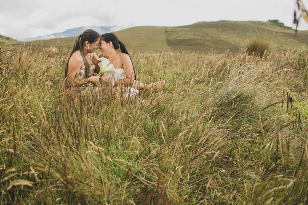 пара женщин, сидящих на открытом лугу рядом с горами и смотрящих друг на друга лицом к лицу - newlywed wedding couple human hair стоковые фото и изображения