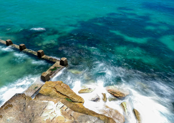 istock Powerful white swirling waves (blurred motion) crashing into rocky coastline 1928574497