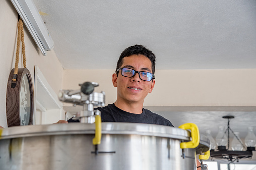Latino man adjusting machinery for craft beer production