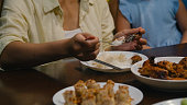 Closeup of Asian family eating chinese food and having fun dinner sitting at dining table at backyard outside home at night. Multi-generation family enjoying spending together.