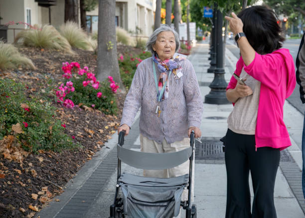 istock Senior woman walking using a mobility walker on the pedestrian footpath, chatting to her daughter. California. 1928805177