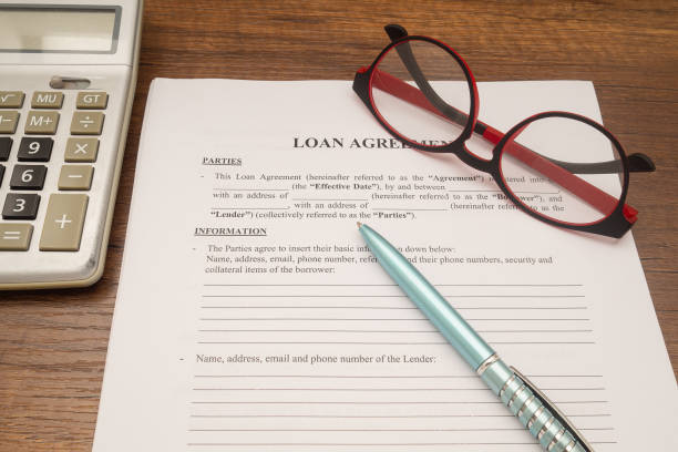 istock Loan agreement documents, a pen, eyeglasses, and a calculator on the office desk. 1928903127