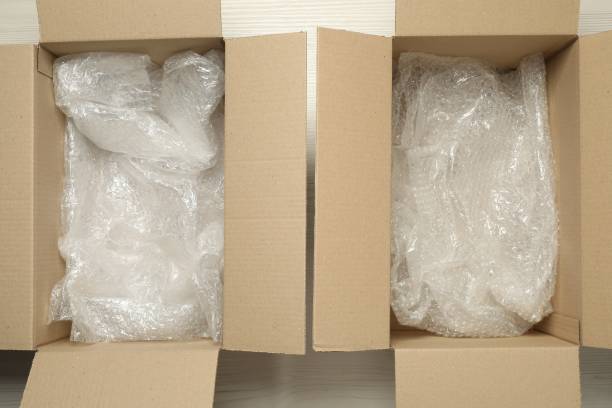 istock Open cardboard boxes with bubble pack on white wooden floor, flat lay 1928947429