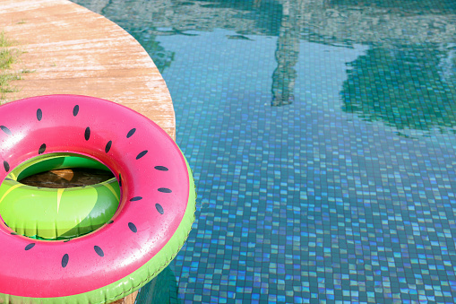 Inflatable rings on wooden deck near swimming pool. Luxury resort