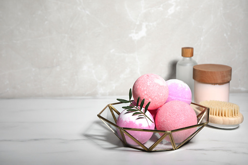Beautiful composition with aromatic bath bombs on white marble table, space for text