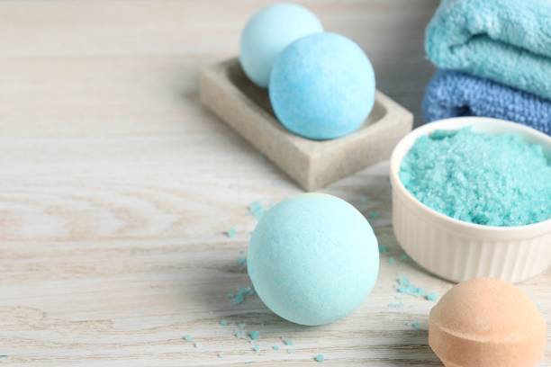 istock Beautiful aromatic bath bombs and sea salt on light wooden table. Space for text 1928990259