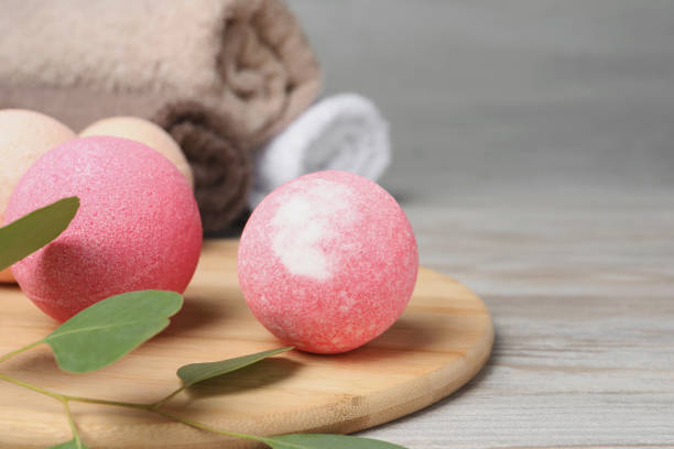 istock Beautiful aromatic bath bombs and green branch on light wooden table, closeup. Space for text 1928990770