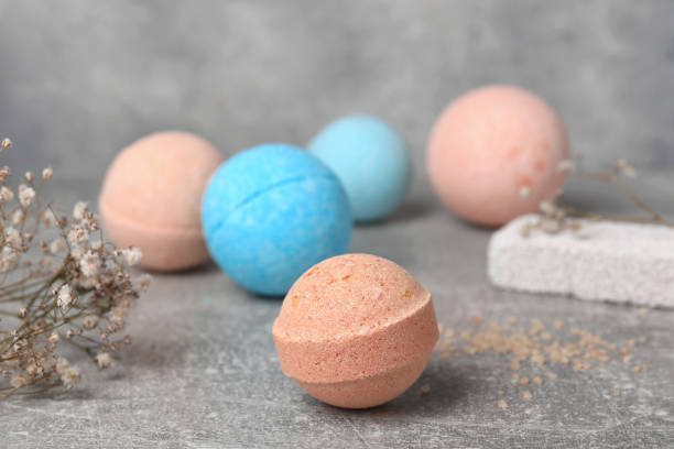 istock Beautiful aromatic bath bombs and gypsophila flowers on light grey table, space for text 1928991804