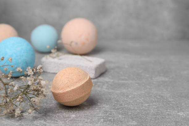 istock Beautiful aromatic bath bombs and gypsophila flowers on light grey table, space for text 1928992321