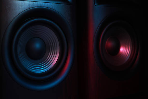 Modern sound speakers in neon light on black background, closeup