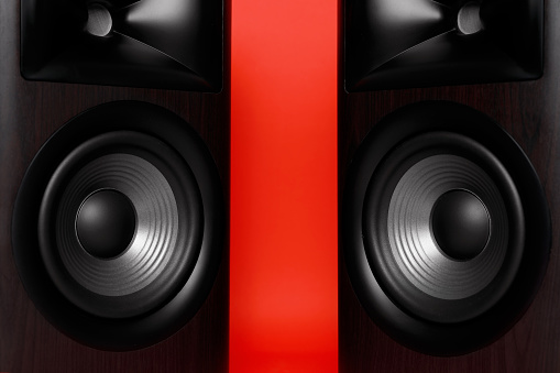 Modern wooden sound speakers on red background, closeup