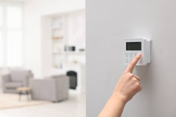 istock Woman adjusting thermostat on white wall indoors, closeup and space for text. Smart home system 1929014817