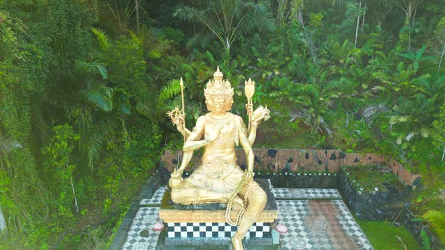 Aerial view on Gold Buddha Statue surrounded by Jungle in Bali, Indonesia.