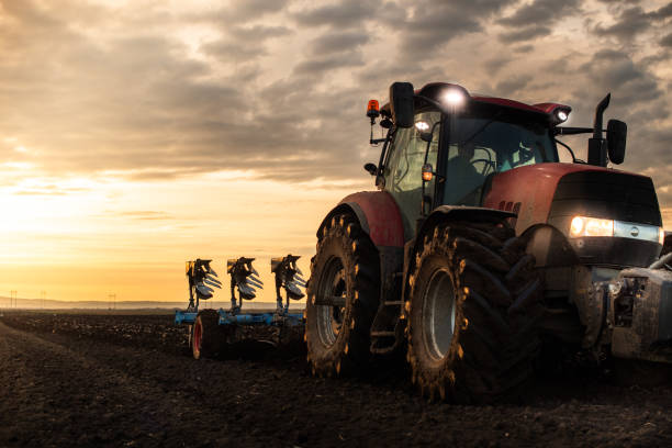 Tractor on the field during sunset. stock photo