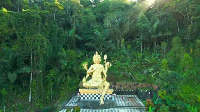 Aerial view on Gold Buddha Statue surrounded by Jungle in Bali, Indonesia.