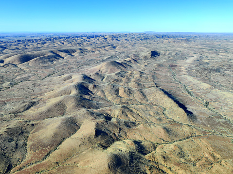 An aerial view of a beautiful desert covered with with yellow and red sand and rocky mountains