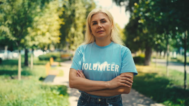 Portrait of confident woman volunteer standing in a park, charity organization