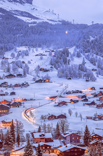 The fairytale-like Grindelwald villages with wooden chalets covered with snow in cold winter season at twilight in Swiss Alps