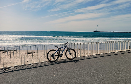 A bicycle leaning against a beach railing on a sunny day on the beach in Portugal